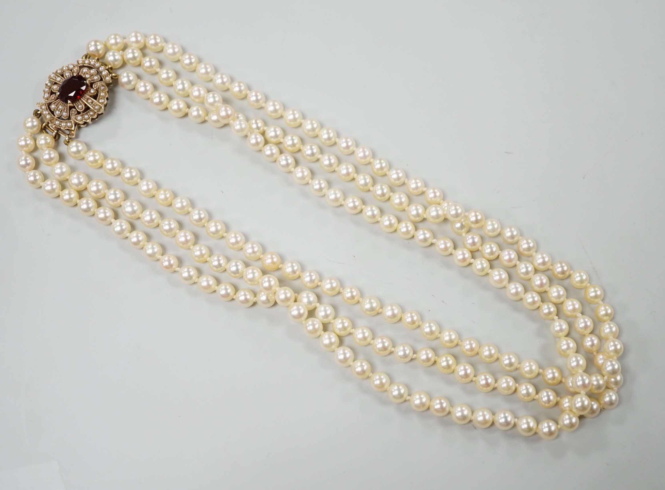 A 1960's triple strand cultured pearl choker necklace by Cropp & Farr, with 9ct gold, garnet and seed pearl set clasp, 39cm.